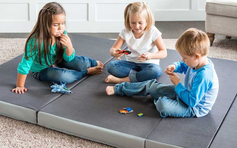 Kids playing on a foldable mattress on the floor
